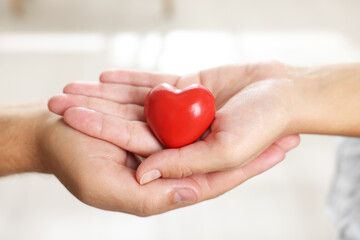 Little girl and her father with red heart figure indoors, closeup