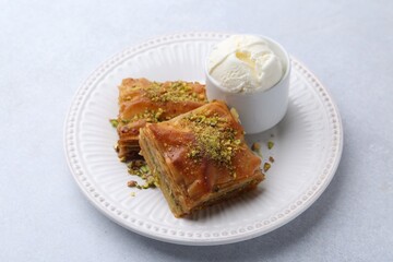 Delicious baklava with crushed nuts and ice cream on grey table, closeup