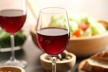 Red wine and delicious dinner served on table, closeup