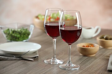 Red wine and delicious dinner served on wooden table