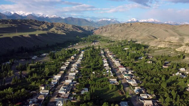Aerial flyover of the town of Kyzyl-Tuu with the Tian Shan mountains in the background in Kyrgyzstan.