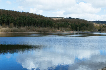 Scenic Lake View with Rolling Hills and Sheep Under a Blue Sky