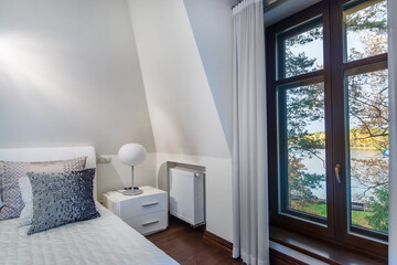 Elegant bedroom interior with white decor. Picturesque view of the lake on a clear .autumn day from the bedroom window of a luxurious country mansion.