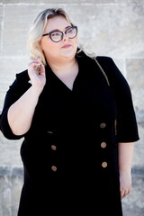 A fat woman wearing a strict dress and glasses is walking in the park