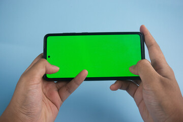 Hands Holding Smartphone With Green Screen and Blue Background