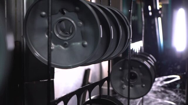 Close up view of dipping hanged metal pieces in the electropaint tank for the cataphoresis or paint process on the automated conveyor in a factory.