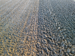 An aerial view of freshly plowed farmland showing contrasting soil textures with visible furrows...