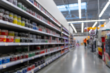 Blurred defocused image of long shelves filled with colorful paint cans in a construction supermarket