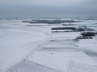 Aerial view of snow-covered fields with a cloudy sky in the background