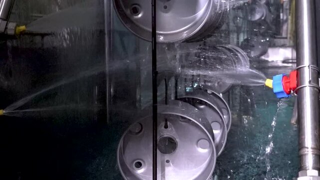 Close up view of dipping hanged metal pieces in the electropaint tank for the cataphoresis or paint process on the automated conveyor in a factory.