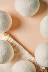 Close-up of wool dryer balls scattered around a cotton drawstring bag on a soft beige background....