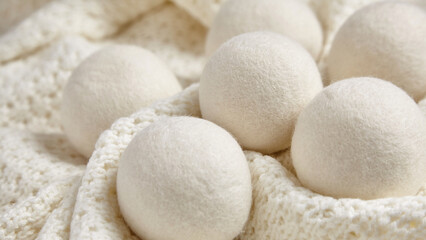 Wool dryer balls resting on a cozy, textured white knitted fabric. Eco-friendly and reusable, ideal for reducing static and wrinkles in laundry