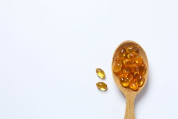 Capsule of omega 3, 6, 9 fish oil, vitamin, food supplement in wooden spoon on white background 