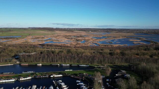 Aerial drone footage panning over Lemonroyd Marina and Waterside beside the Aire and Calder Navigation and St Aidans Nature Reserve. Canal boats and house boats moored. West Yorkshire, UK