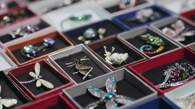 Assorted decorative brooches displayed in small boxes at a jewelry showcase