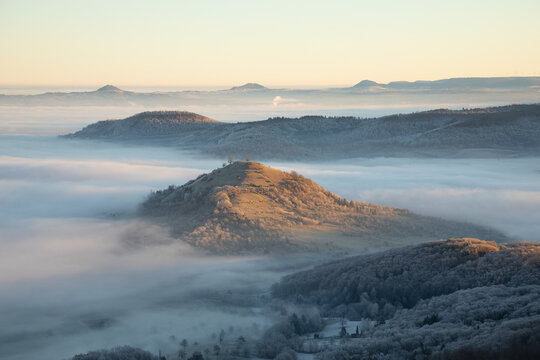 Blick vom Breitenstein, Ochsenwang, Schw&auml;bische Alb auf die drei Kaiserberge - Hohenstaufen, Stuifen und Rechberg. Im Vordergrund die Limburg bei Weilheim Teck im Winter zum Sonnenaufgang mit Nebel.
