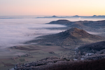Blick vom Breitenstein, Ochsenwang, Schwäbische Alb auf die drei Kaiserberge - Hohenstaufen, Stuifen und Rechberg. Im Vordergrund die Limburg bei Weilheim Teck im Winter zum Sonnenaufgang mit Nebel.