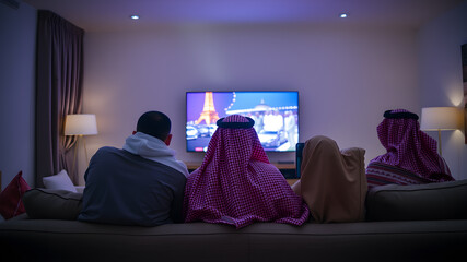 Naklejka premium back view of a Saudi family watching tv in the living room and sitting on a couch, back view. Generative AI
