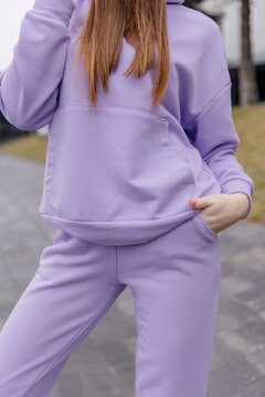Cute girl model in a sporty comfortable casual purple outfit with a hoodie and sweatpants posing