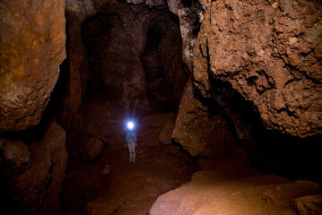 Speleologist explores an underground cave, geologist studies hole rock mountain