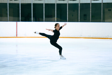 Girl figure skater trains on skates on the ice.