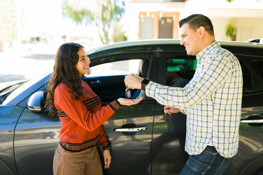 Father happily passing car keys to his teenage daughter, guiding her in her first driving lesson