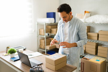 Latin entrepreneur scanning shipping label on boxes in his office or warehouse, managing his...