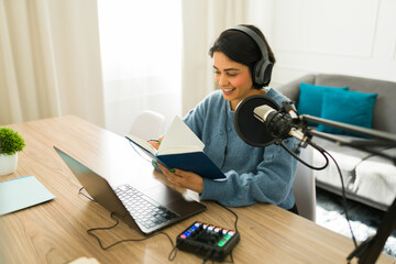 Beautiful woman wearing headphones, writing notes during live radio broadcast from personal home...