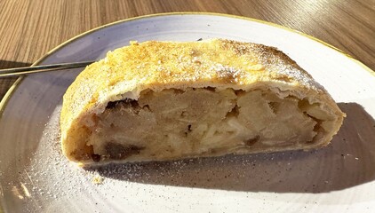 Delicious slice of apple strudel with crisp pastry and sweet filling on plate