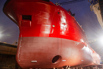 A ship standing in a dry dock at night under the light of lanterns.