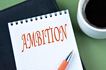 AMBITION - word in notebook on green background with cup of coffee