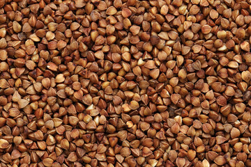 Buckwheat groats, top view. Raw large buckwheat grains, uncooked porridge. Buckwheat background. Raw buckwheat texture background, brown grains pattern