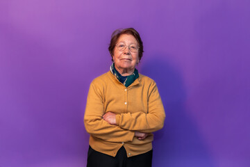 Confident senior professor posing with crossed arms on purple background