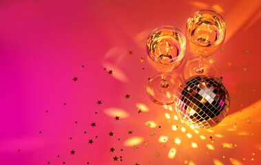 Champagne and disco ball on shining pink background. Celebration, festive, party time concept. Birthday, Christmas, New year's eve, Carnival, masquerade.