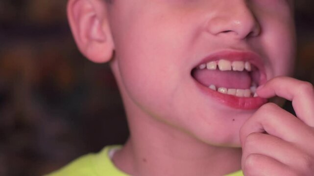 A boy rocks a baby tooth in close-up