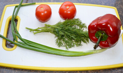 fresh vegetables, ingredients for salad on the kitchen board. ripe bell peppers, tomatoes, green onions and a small bunch of dill. proper nutrition. vegetarianism. diet and healthy lifestyle