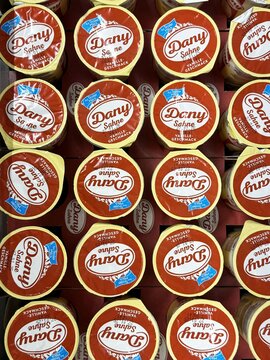 Rows of dany sahne german pudding cups in red and yellow packaging displayed on shelf
