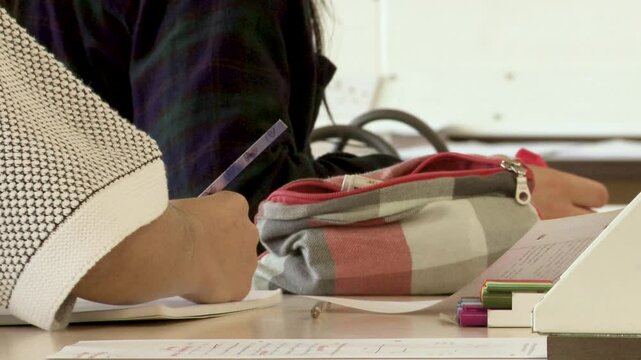 A close-up shot of a student&rsquo;s hand writing in a workbook, capturing focus, learning, and classroom engagement.