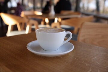 Cup of aromatic coffee on wooden table in cafe