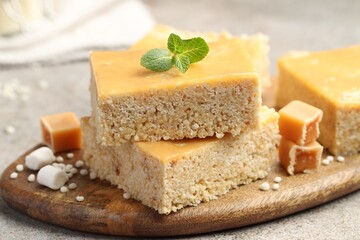 Delicious puffed rice bars, candies and mint on gray textured table, closeup