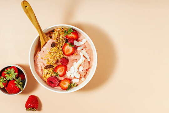 Smoothie bowl topped with strawberries, raspberries, and granola, healthy breakfast