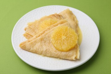 Delicious Crepes Suzette on green background, closeup