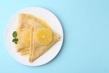 Delicious Crepes Suzette on light blue background, top view. Space for text