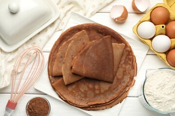 Delicious chocolate crepes and ingredients on white wooden table, flat lay