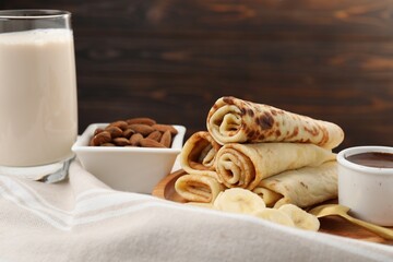Delicious crepes served with chocolate sauce and banana on table, closeup