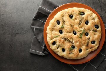 Delicious focaccia bread with olives and rosemary on grey table, top view. Space for text