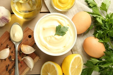 Delicious mayonnaise sauce in bowl and ingredients on wooden table, flat lay