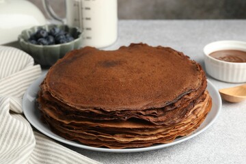 Delicious chocolate crepes with sweet paste and blueberries on light grey table, closeup