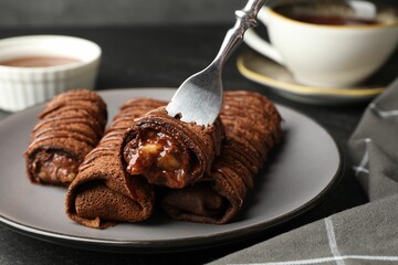 Delicious chocolate crepes with sweet paste and nuts on table, closeup