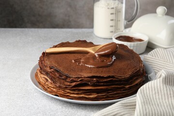 Delicious chocolate crepes with sweet paste on light grey table, closeup